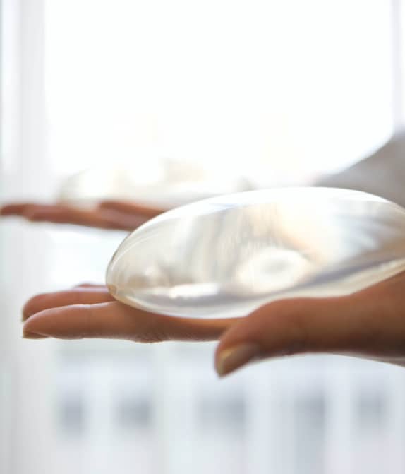 close up of hand holding breast implant