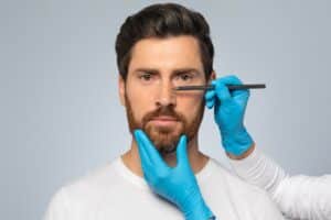 Doctor,Making,Marks,On,Male,Patient's,Face,,Middle,Aged,Man