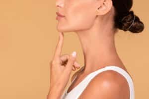 A profile shot of a woman pointing to her chin