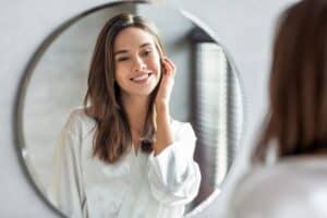Woman smiling while looking at herself in the mirror after facelift in Salt Lake City, UT