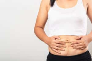 Mother holding her loose midsection skin, needing body contouring in Salt Lake City
