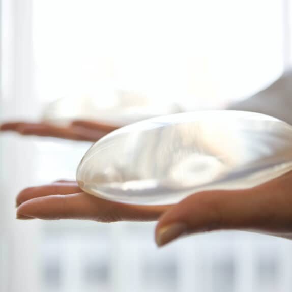 close up of hand holding breast implant